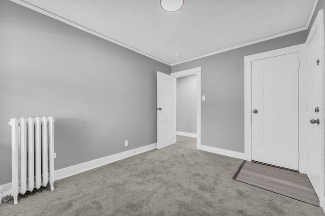 unfurnished bedroom featuring crown molding, radiator heating unit, and light carpet