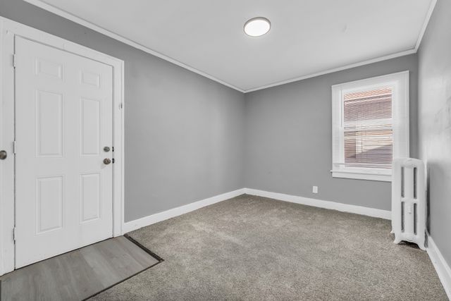 carpeted empty room with crown molding