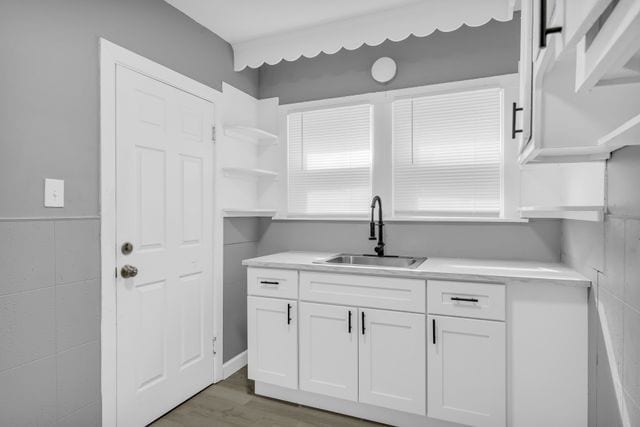 kitchen with sink, dark wood-type flooring, white cabinets, and tile walls