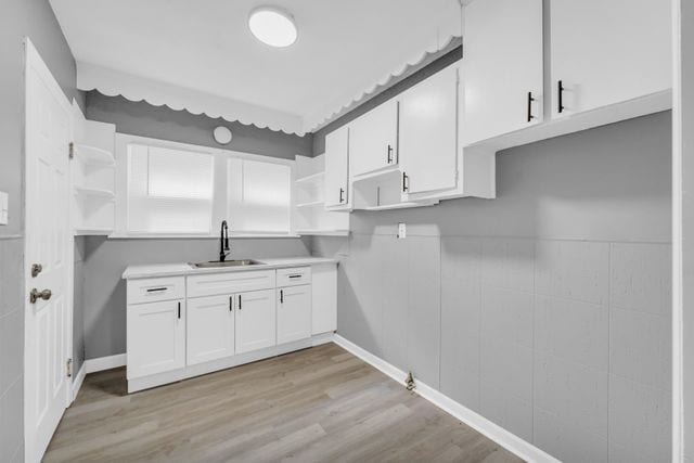 kitchen featuring white cabinetry, sink, and light hardwood / wood-style flooring