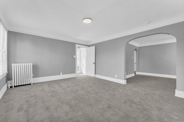 carpeted spare room with ornamental molding and radiator heating unit