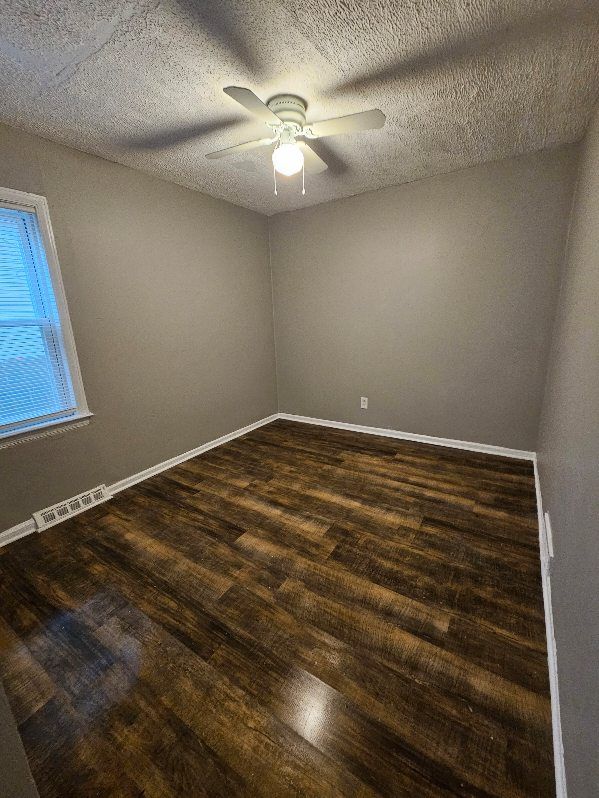 unfurnished room with dark hardwood / wood-style flooring, a textured ceiling, and ceiling fan