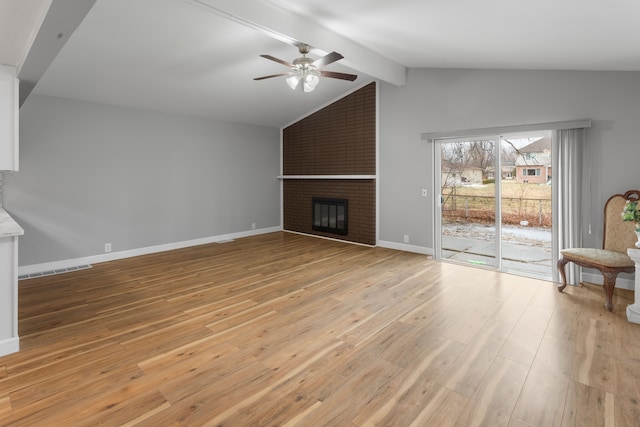 living room featuring ceiling fan, a brick fireplace, vaulted ceiling with beams, and light hardwood / wood-style floors