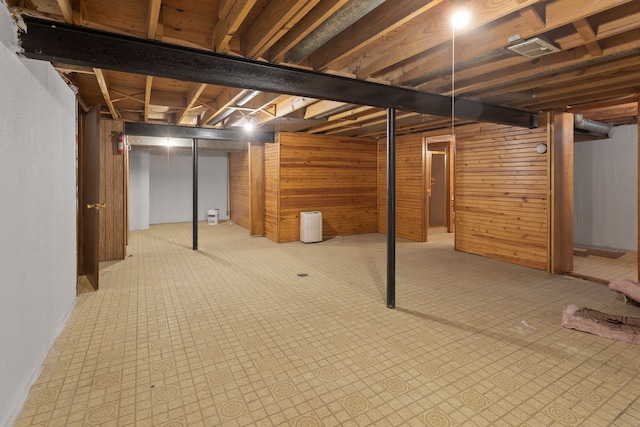 basement featuring wooden walls