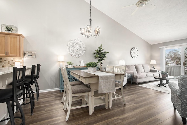 dining room featuring ceiling fan with notable chandelier, high vaulted ceiling, and dark hardwood / wood-style floors