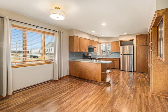 kitchen featuring sink, light hardwood / wood-style flooring, kitchen peninsula, and appliances with stainless steel finishes