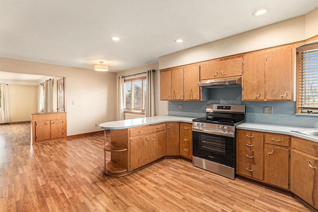 kitchen featuring stainless steel electric stove, kitchen peninsula, sink, and light hardwood / wood-style flooring