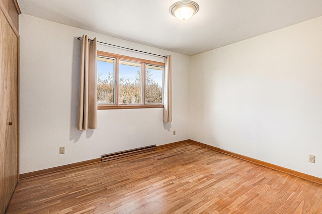 unfurnished room featuring wood-type flooring and a baseboard radiator