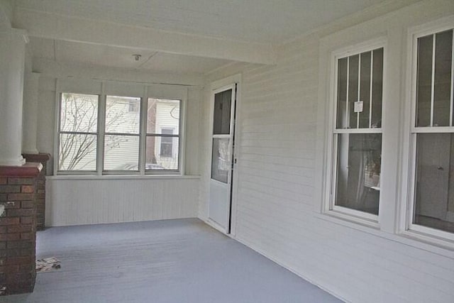 unfurnished sunroom featuring beamed ceiling