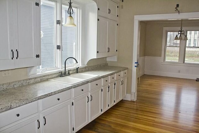 kitchen with white cabinetry, sink, decorative light fixtures, and light wood-type flooring