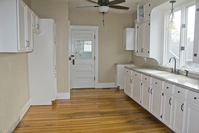 kitchen with pendant lighting, sink, light hardwood / wood-style flooring, and white cabinets