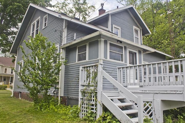 307 New York Ave, Dowagiac, MI 49047 - view of side of home with a chimney, a wooden deck, stairs, and a lawn