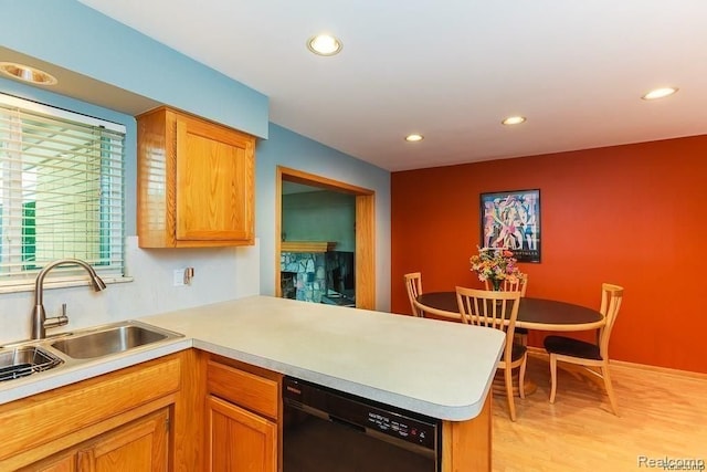 kitchen featuring dishwasher, sink, light wood-type flooring, and kitchen peninsula