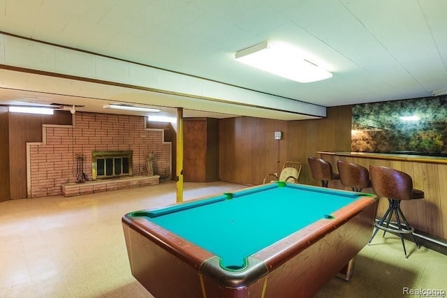 playroom featuring a fireplace and wood walls