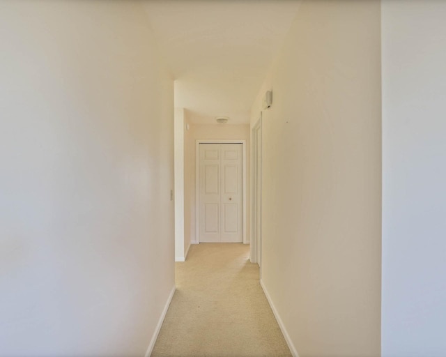 hall with baseboards and light carpet