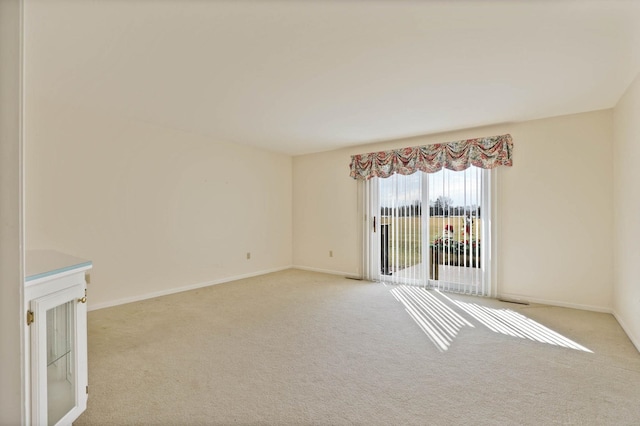 unfurnished room featuring baseboards and light carpet