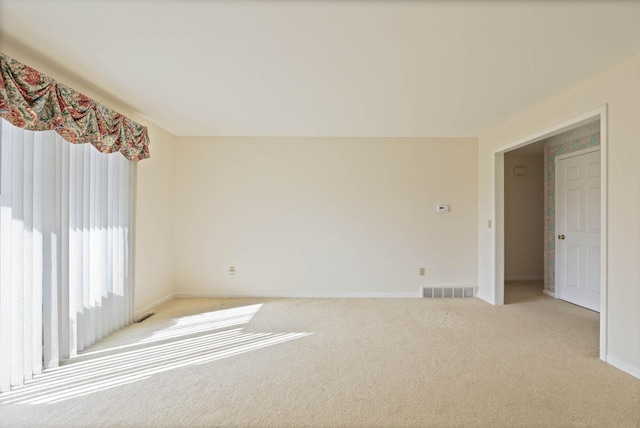 empty room with light colored carpet, visible vents, and baseboards