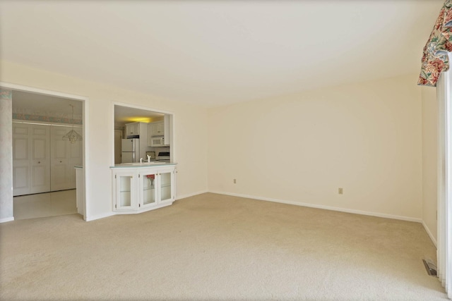 spare room with baseboards, light carpet, and visible vents