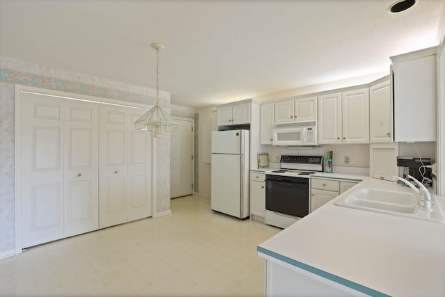 kitchen featuring white appliances, light floors, a sink, hanging light fixtures, and light countertops