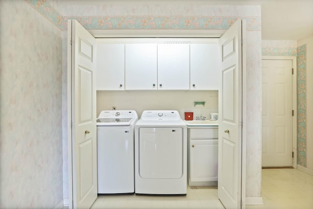 laundry area featuring a sink, washing machine and dryer, cabinet space, wallpapered walls, and baseboards