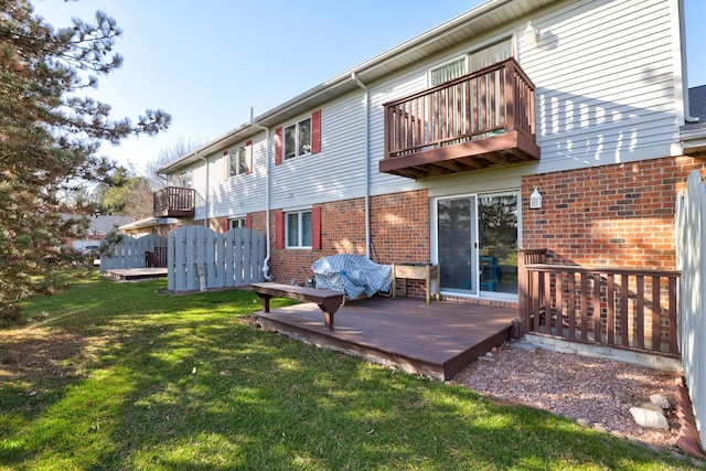 back of house with brick siding, a lawn, and a balcony