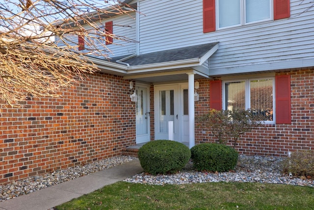 entrance to property with brick siding and roof with shingles