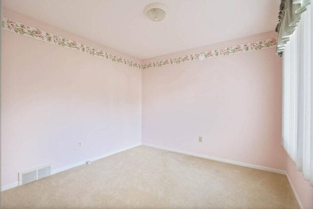 carpeted empty room featuring baseboards and visible vents