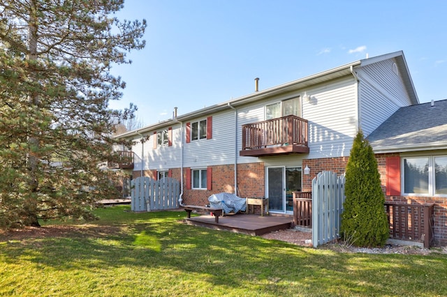 back of property featuring brick siding, a balcony, and a lawn