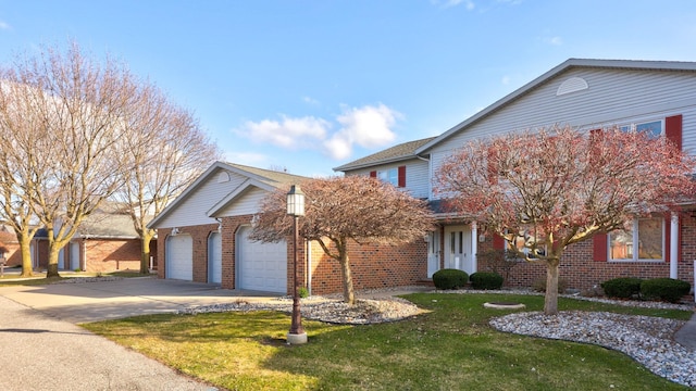 traditional-style house with brick siding, driveway, an attached garage, and a front yard