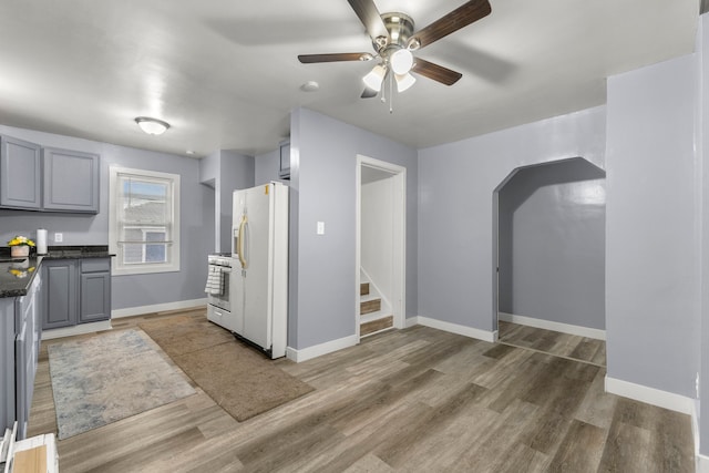 kitchen with gray cabinetry, white appliances, wood-type flooring, and ceiling fan