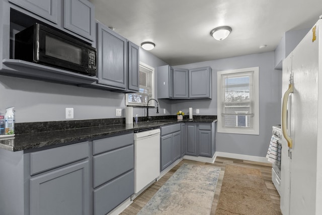 kitchen featuring hardwood / wood-style floors, sink, gray cabinetry, a healthy amount of sunlight, and white appliances