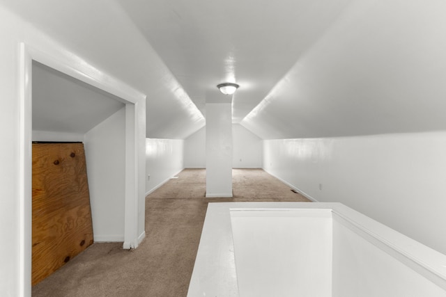 bonus room with vaulted ceiling and light carpet