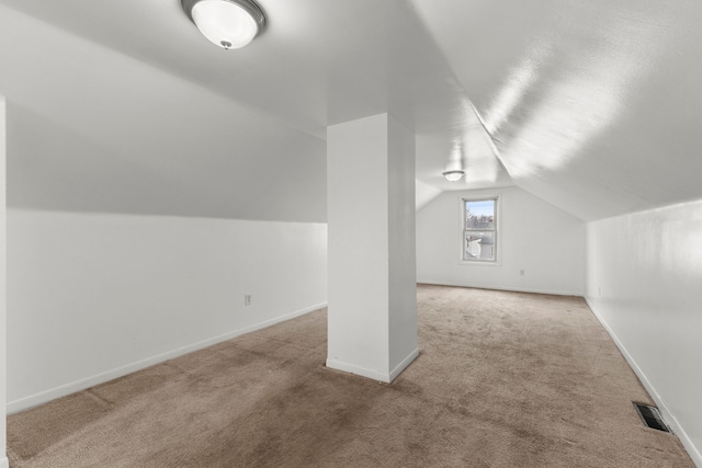 additional living space featuring light carpet and vaulted ceiling