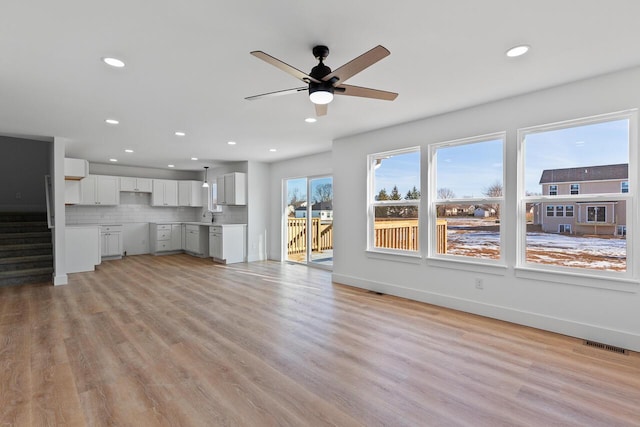 unfurnished living room with ceiling fan, sink, and light hardwood / wood-style floors