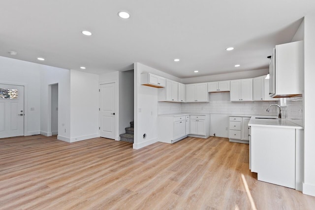 kitchen featuring tasteful backsplash, sink, white cabinets, and light hardwood / wood-style flooring