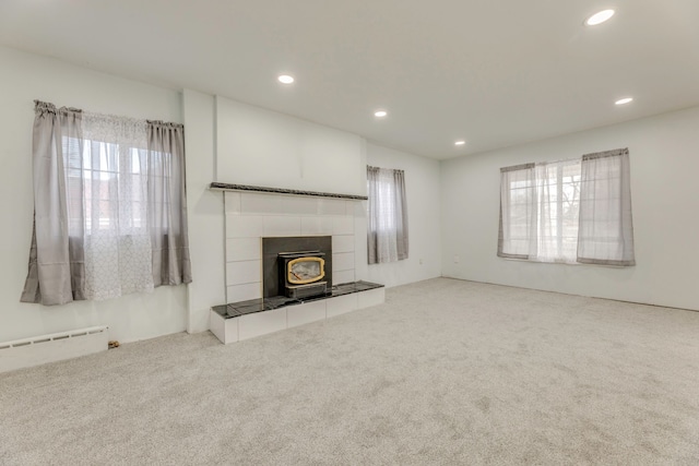 unfurnished living room with a baseboard radiator, a healthy amount of sunlight, and carpet