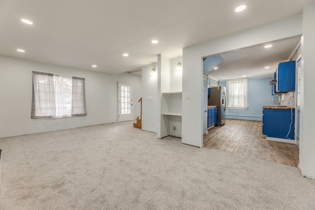 unfurnished living room featuring a baseboard radiator and carpet