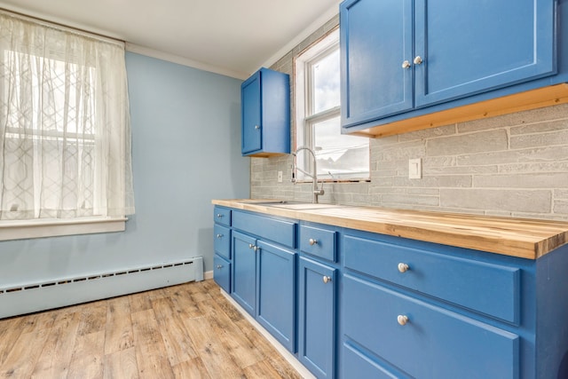 kitchen featuring blue cabinets, butcher block counters, sink, baseboard heating, and backsplash