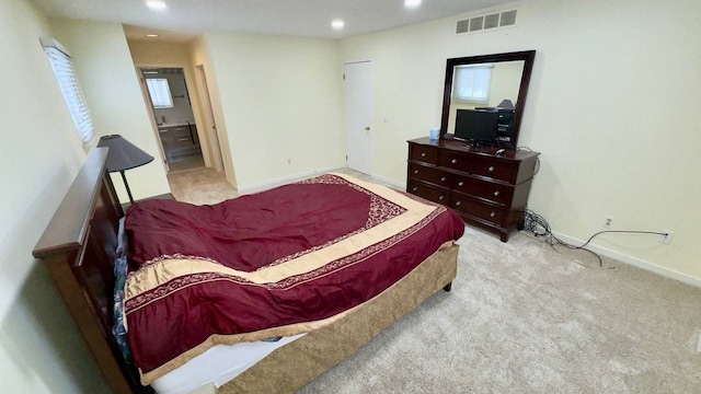 bedroom with light carpet and ensuite bath