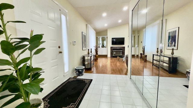 entrance foyer with lofted ceiling, light tile patterned floors, and a high end fireplace