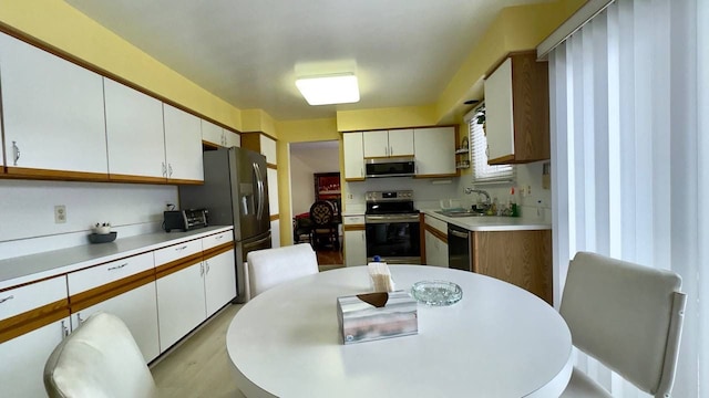 kitchen featuring white cabinetry, stainless steel appliances, sink, and light hardwood / wood-style flooring