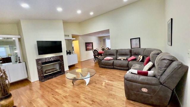 living room featuring a fireplace, high vaulted ceiling, and light hardwood / wood-style flooring