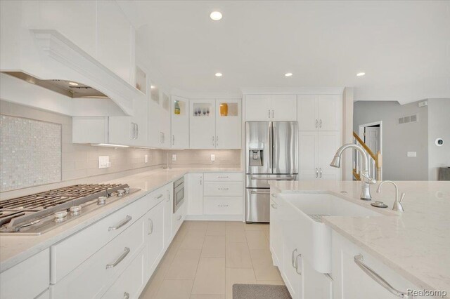 1611 Harwood Dr, Oxford, MI 48371 - kitchen featuring appliances with stainless steel finishes, decorative backsplash, white cabinets, light stone countertops, and light tile patterned flooring