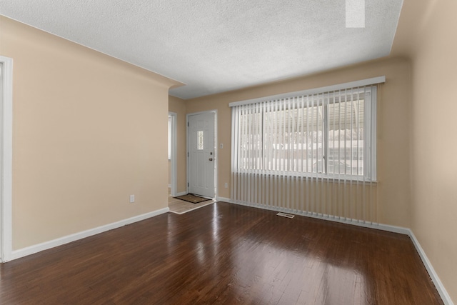 empty room with hardwood / wood-style floors and a textured ceiling