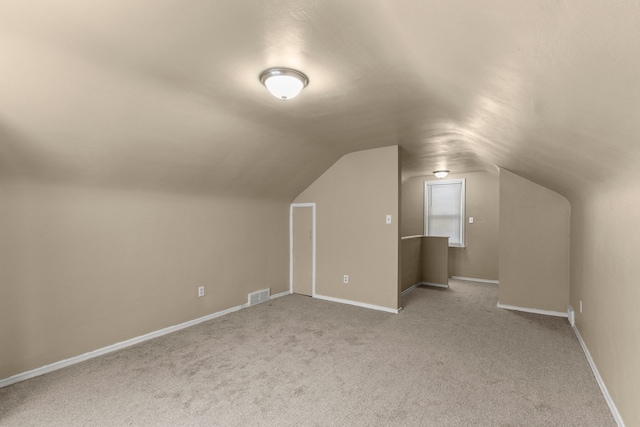 additional living space with light carpet and vaulted ceiling