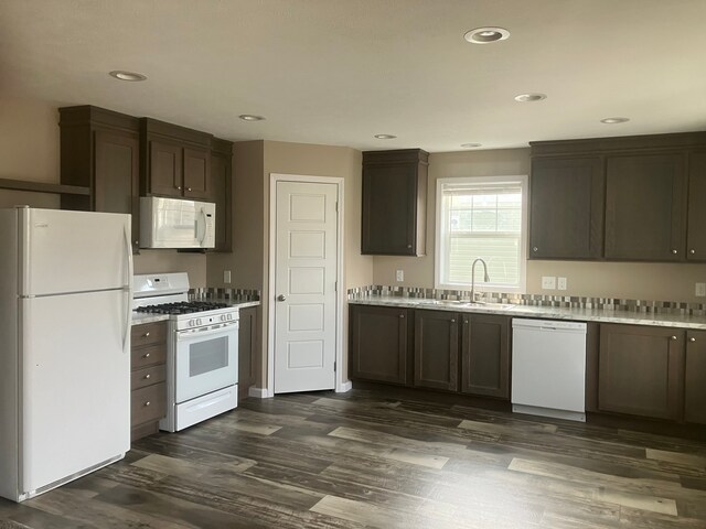 kitchen with dark brown cabinetry, sink, dark wood-type flooring, and white appliances