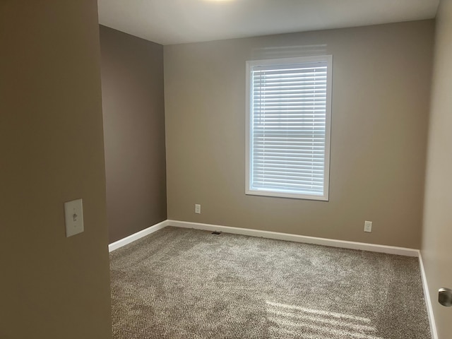 carpeted spare room featuring baseboards