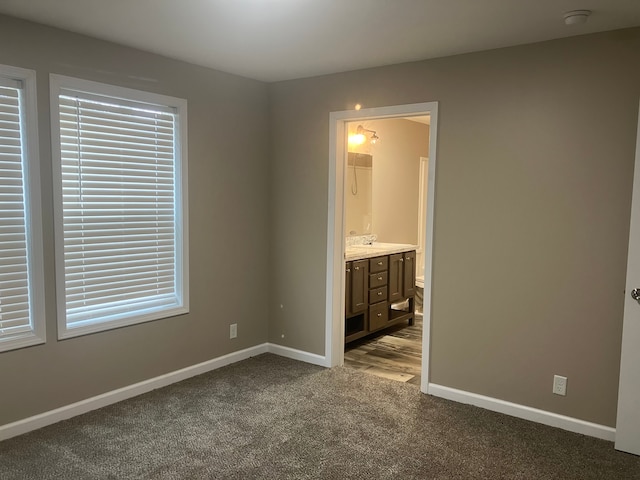 unfurnished bedroom with light carpet, connected bathroom, and baseboards