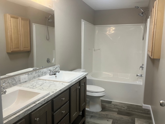 bathroom featuring double vanity, toilet, shower / tub combination, wood finished floors, and a sink