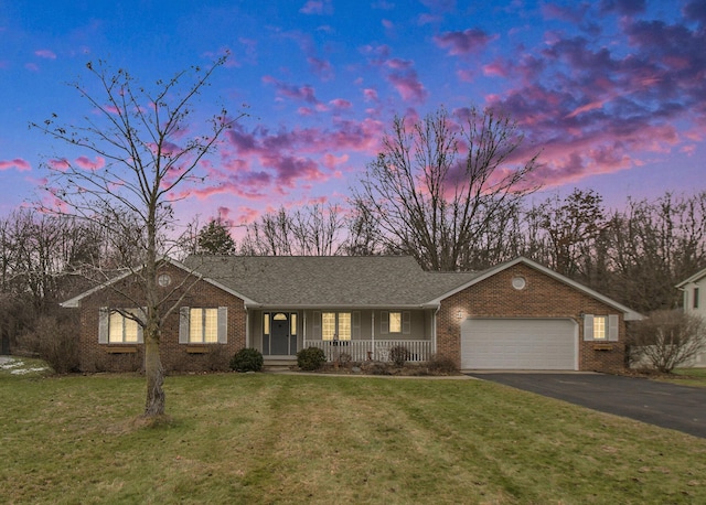 single story home featuring a garage, a yard, and covered porch